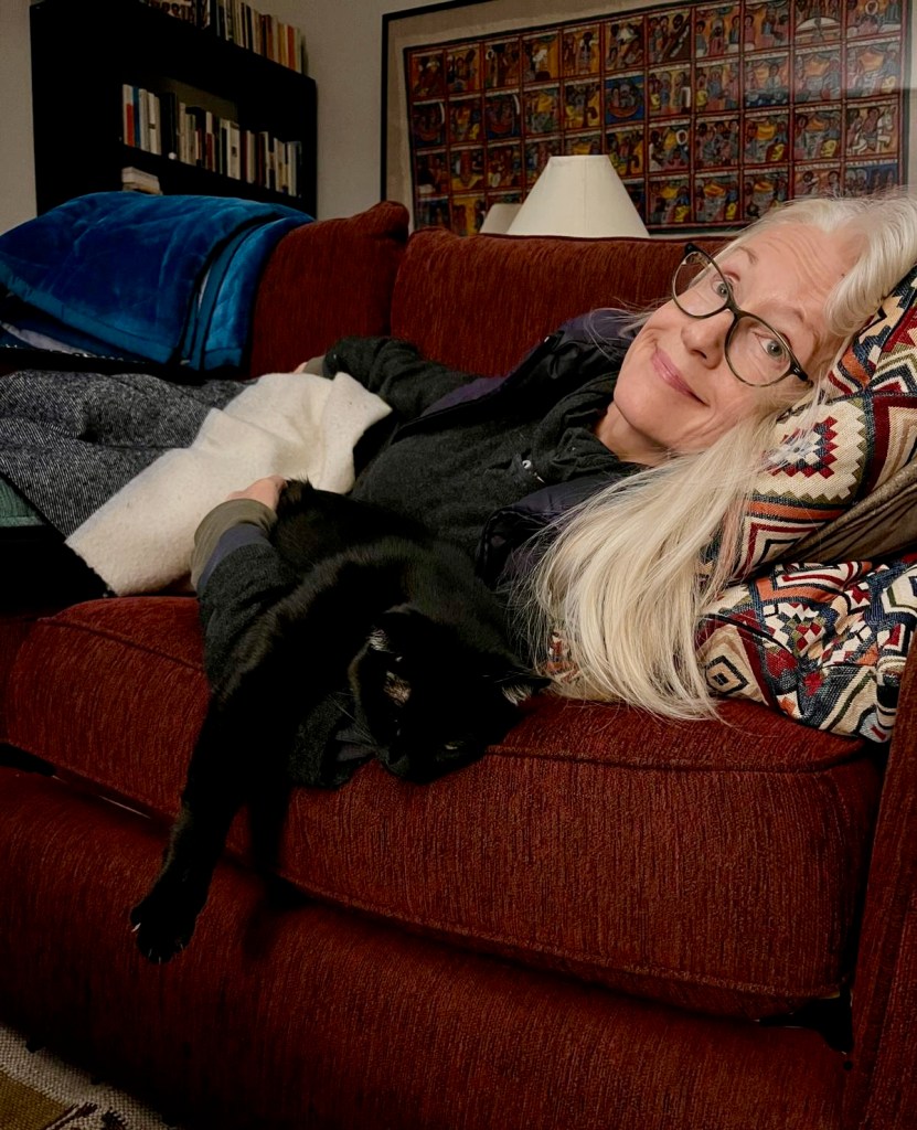 Sandra lying on a couch with her black cat Ronan
